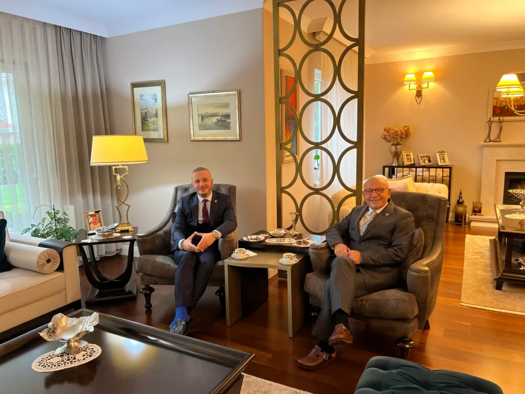 Two men in suits sitting in a living room.