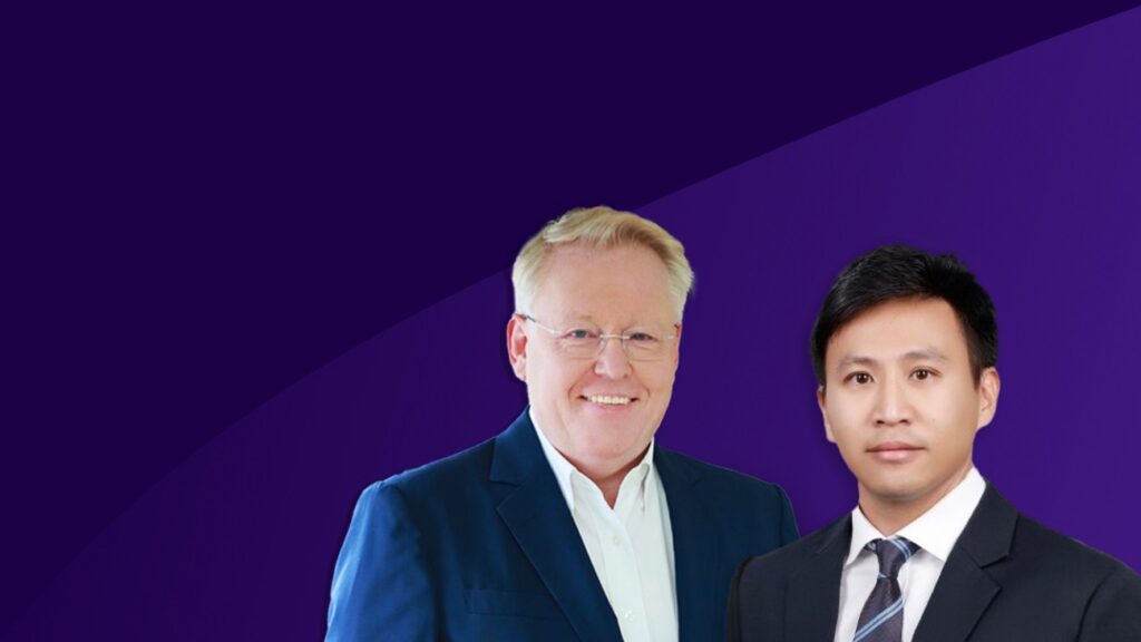 Two men in professional attire are facing the camera, standing against a purple background with a curved design. The man on the left wears glasses and a blue suit; the man on the right, reminiscent of business leaders from Southeast Asia, wears a dark suit and tie.
