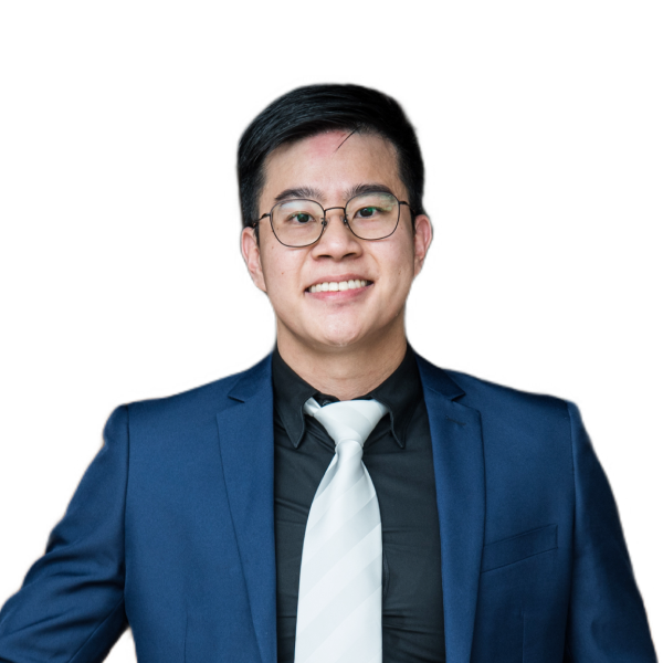 A person wearing glasses, a dark shirt, a light tie, and a blue blazer is smiling and posing for a photo against a plain background.