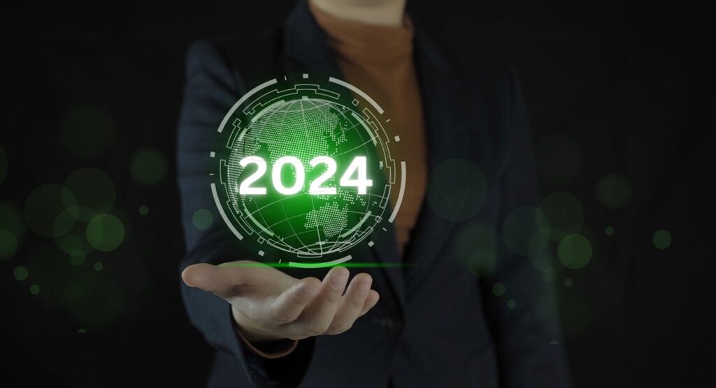 Person holding a digital hologram with "2024" and a globe design, set against a dark background.