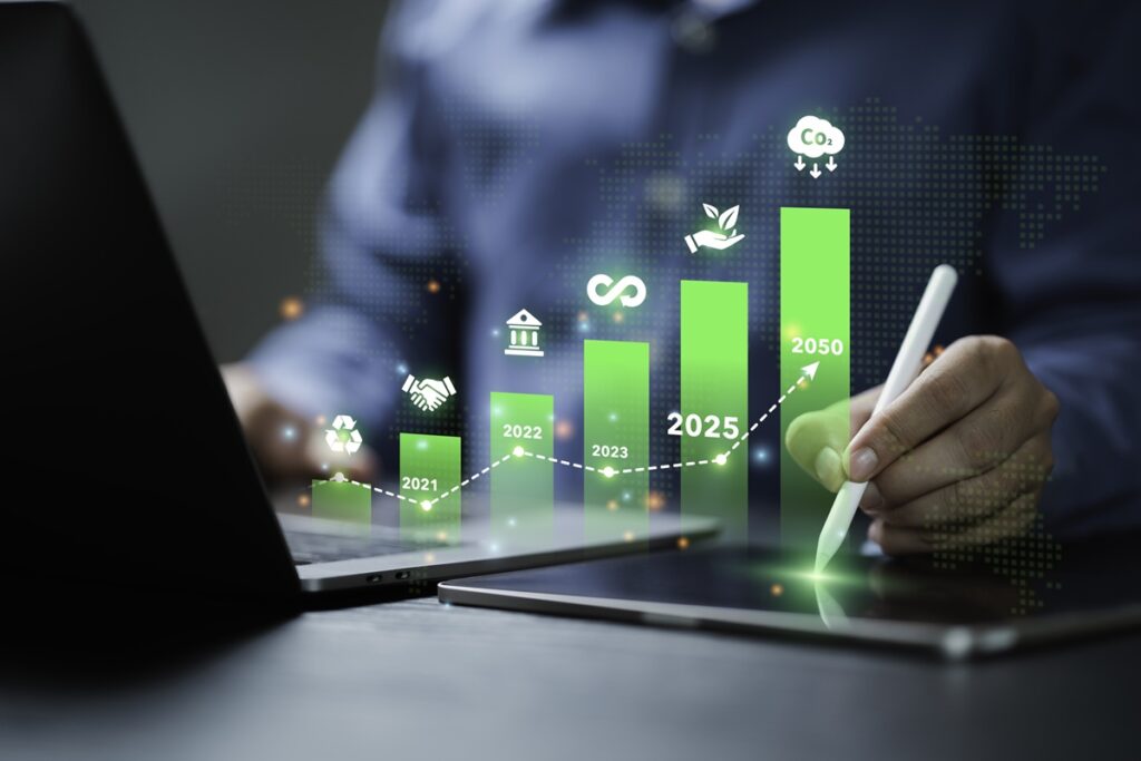 Person with a stylus pointing at a bar graph showing growth from 2020 to 2050 with sustainability icons.