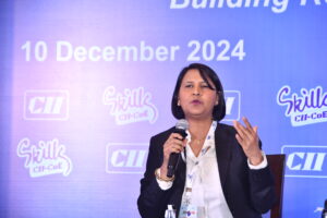 Woman showcasing her skills at a conference, wearing a lanyard, microphone in hand. Date: 10 December 2024.