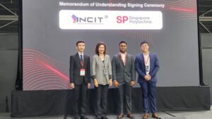 Four people stand on stage at a Memorandum of Understanding signing ceremony.